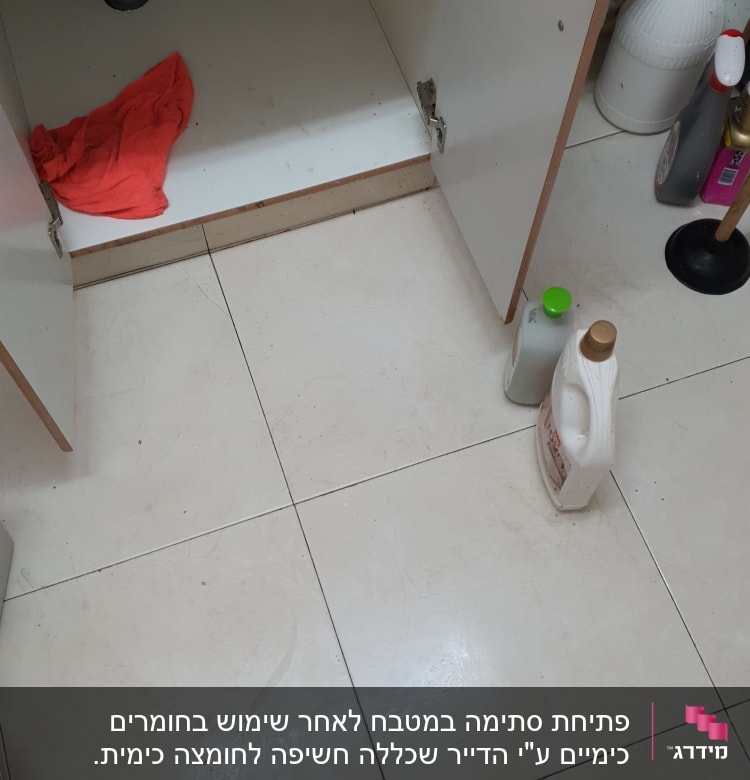 ארון פתוח עם צינור, מטלית אדומה וחומרי ניקוי